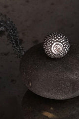 A special birthstone pendant in oxidised silver for April – its centrepiece is a tactile textured ball with a glistening Diamond at the base.