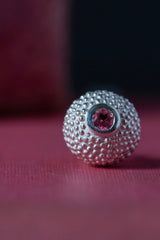 Close up of my special birthstone pendant for October in silver – its centrepiece is a tactile textured ball with a glistening Pink Tourmaline at the base
