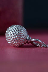 Close up of side view of my special birthstone pendant for October in silver – its centrepiece is a tactile textured ball with a glistening Pink Tourmaline at the base