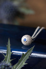 A birthstone pendant for September – a tactile textured ball with a glistening blue Sapphire at the base