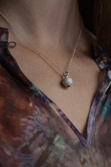 A birthstone pendant for October worn by a model– a tactile textured ball with a glistening Blue Tourmaline at the base