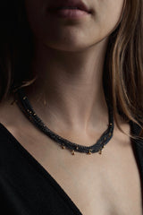 My Five Strand Trace and Pip Necklace worn triple wrapped by a model comprises five delicate oxidised silver chains, decorated with miniature gold plated pips