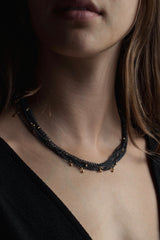 My Five Strand Trace and Pip Necklace worn triple wrapped by a model comprises five delicate oxidised silver chains, decorated with miniature gold plated pips