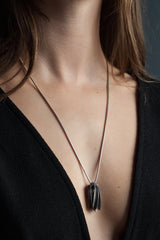 My Aster Pendant Necklace worn by a model like a tassel with its bobbled head fringed with a series of long elegant flowing petals nestled in her decolletage