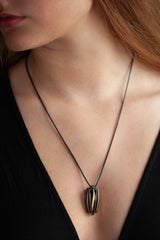My Aster Pendant Necklace worn by a model like a tassel with its bobbled head fringed with a series of long elegant flowing petals nestled in her decolletage