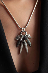 My Dream Catcher Feather and Pod Cluster Pendant necklace is hung with nine charms inspired by the shape of feathers and seed pods worn by model in silver ad oxidised silver