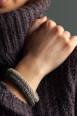 Pair of chunky bracelets in silver and oxidised silver made from lots of daisy charms strung together into a pleasing snake shape