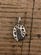 My ladybird charm is a small polished silver oval with different sized spots hanging from small silver ring