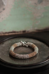 A chunky bracelet in silver and gold plated silver made from lots of daisy charms strung in a pleasing snake shape