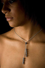 An elegant tassel pendant, worn by a model, on a snake chain threaded with seven tiny textured snow ball beads that elongates the neck