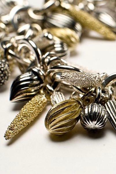 Close up of Mixed Pod Cluster Bracelet in silver and gold plated silverhung with lots of charms inspired by seed pods
