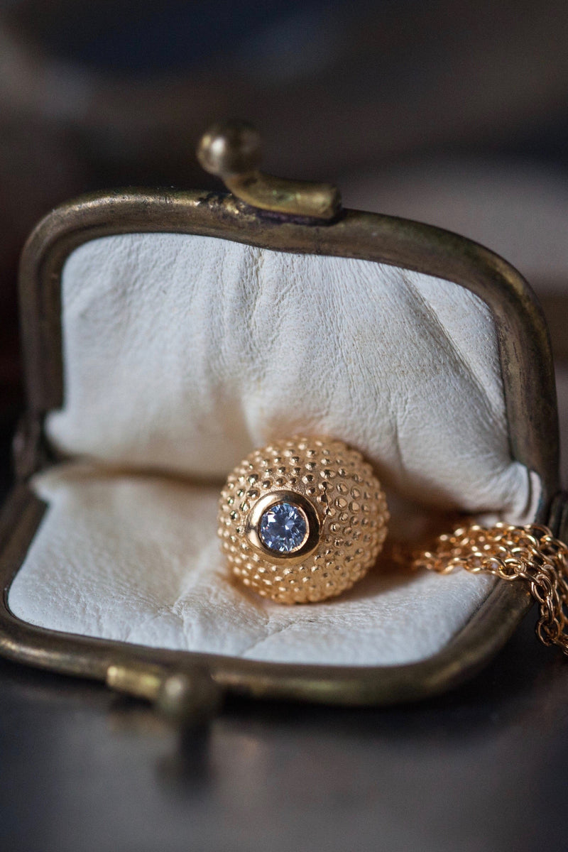 A special birthstone pendant in yellow gold plated silver for April – its centrepiece is a tactile textured ball with a glistening Diamond at the base. 