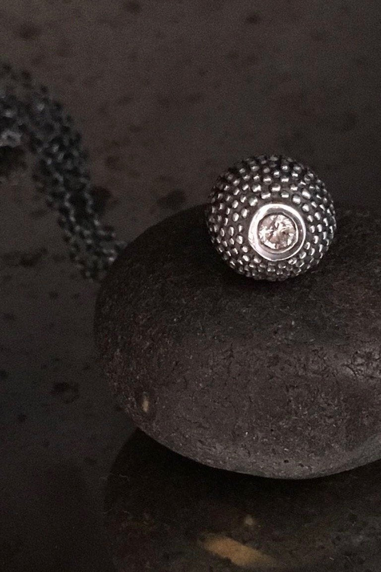A special birthstone pendant in oxidised silver for April – its centrepiece is a tactile textured ball with a glistening Cubic Zirconia at the base. 