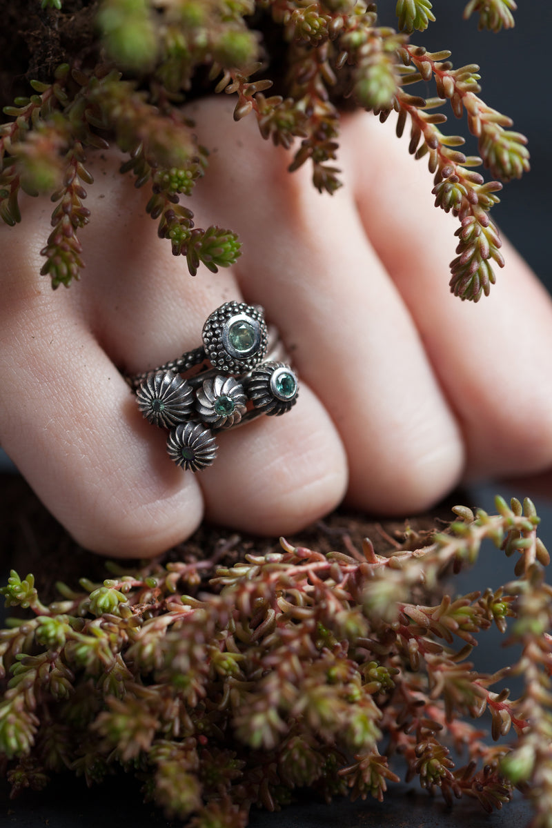 A set of 5 stacking charm rings each set with Alexandrites June's birthstone worn by a model