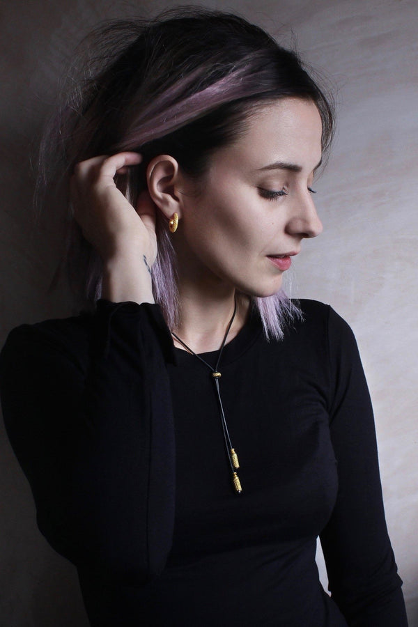 An elegant tassel pendant worn on dark snake chain with two textured lozenge beads that customise how the necklace falls
