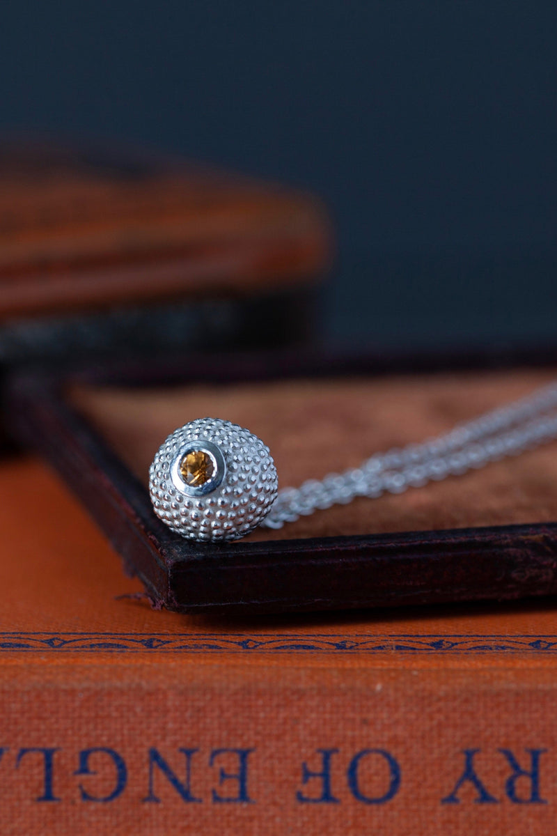 A special birthstone pendant for January – its centrepiece is a tactile textured ball with a glistening orange Spessartite Garnet at the base