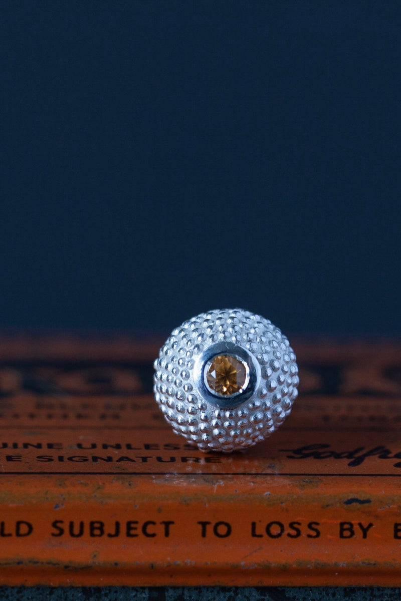 Base view of my special birthstone pendant for January – a tactile textured ball with a glistening orange Spessartite Garnet at the base