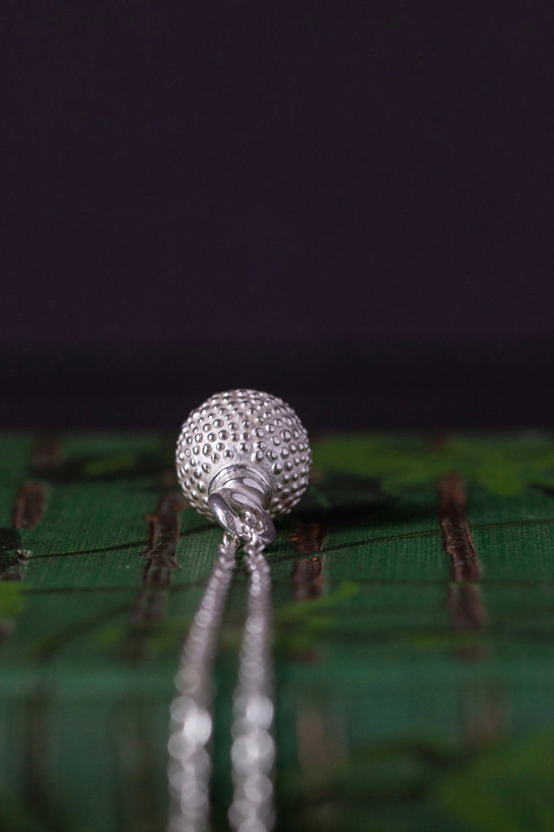 Top view of birthstone pendant for October – a tactile textured ball with a glistening Green Tourmaline at the base
