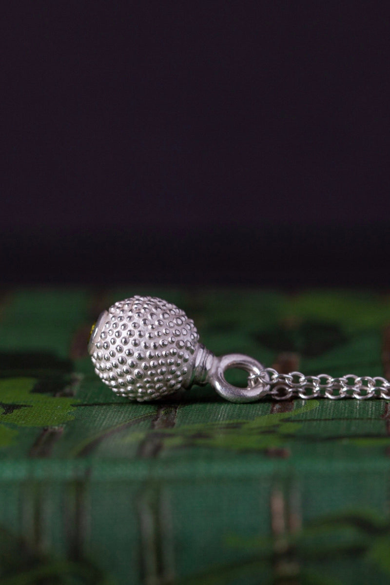 Side view of my birthstone pendant for October – a tactile textured ball with a glistening Green Tourmaline at the base