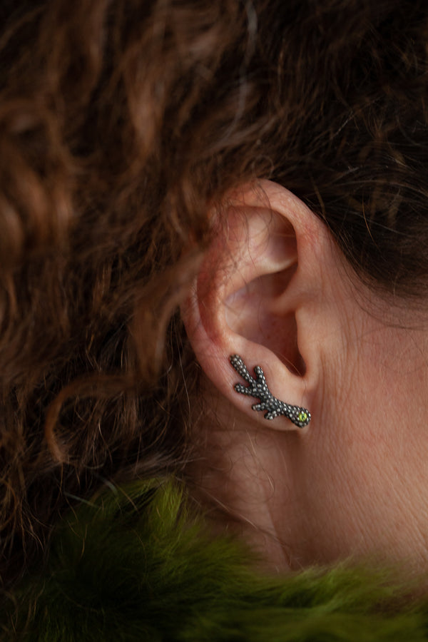 A textured earring, with a shape reminiscent of an antler which sits along the ear lobe