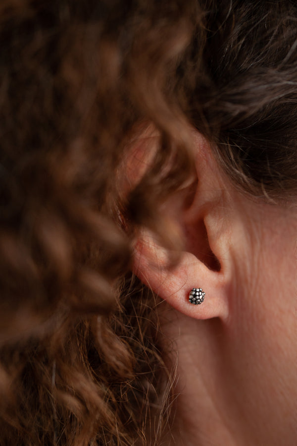 Small stud earrings covered with varying small dots of metal 