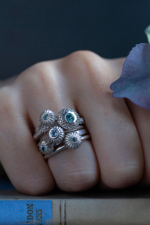 A set of 5 stacking charm rings set with Aquamarines March's birthstone worn by a model 