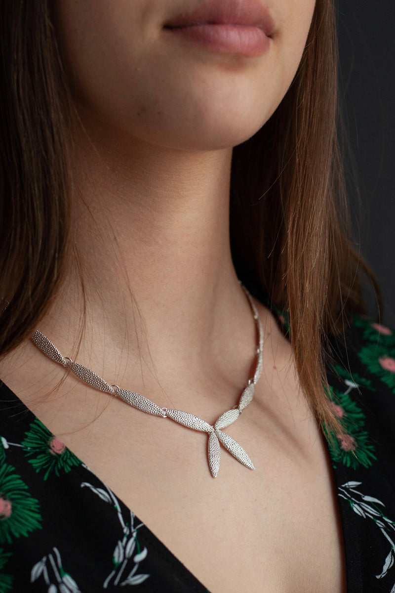 My Petal Necklace wron in silver links textured petals into a chain with two petals as a focal point