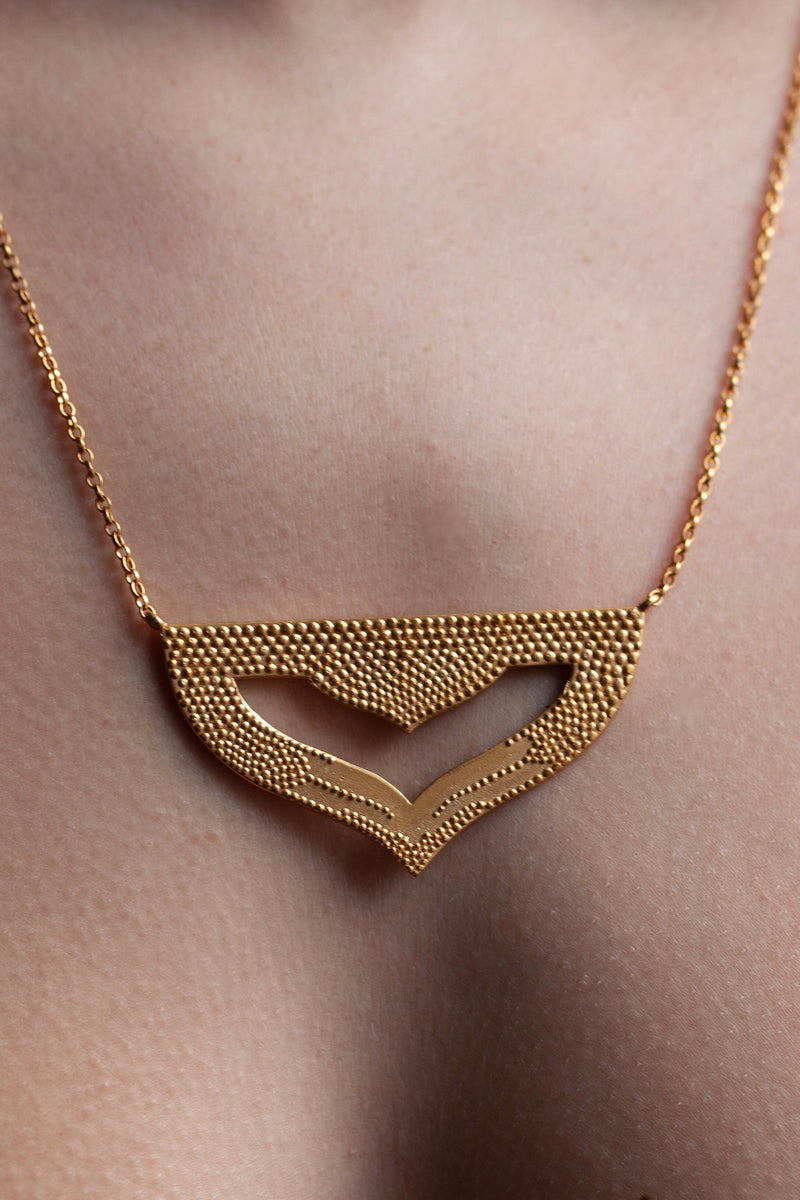  Close up of my Astral Pendant Necklace in yellow gold plated silver worn by a model, inspired by Asian warrior helmets and the necklace I created for the Star Wars film, Solo