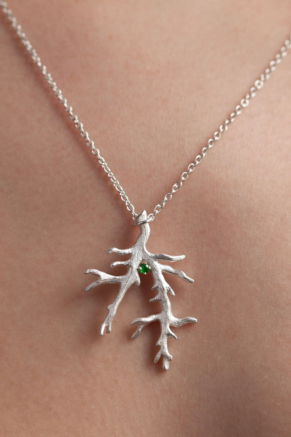 My branch pendant worn by a model set with an Emerald, May's birthstone, hangs from a delicate trace chain