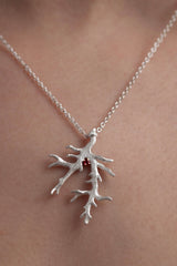 My unusual branch pendant worn by a model set with a Ruby July's birthstone hangs from a delicate trace chain