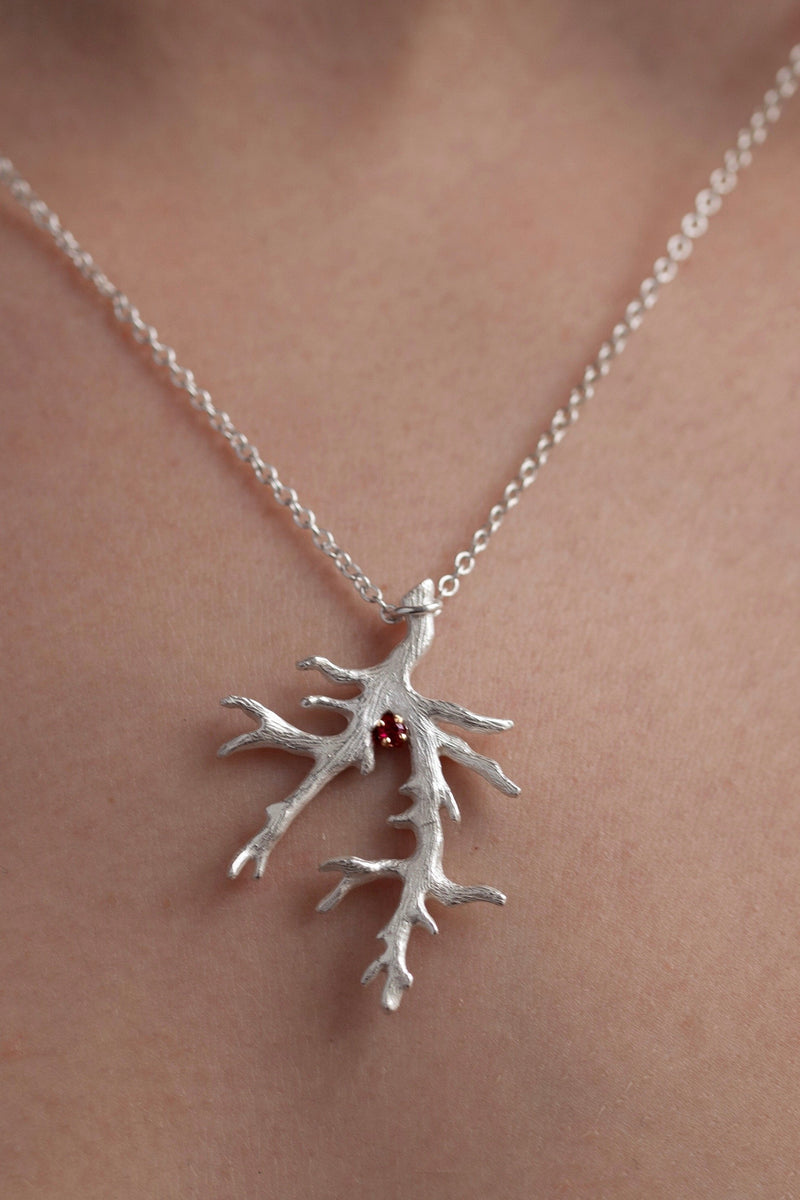 My unusual branch pendant worn by a model set with a Ruby July's birthstone hangs from a delicate trace chain