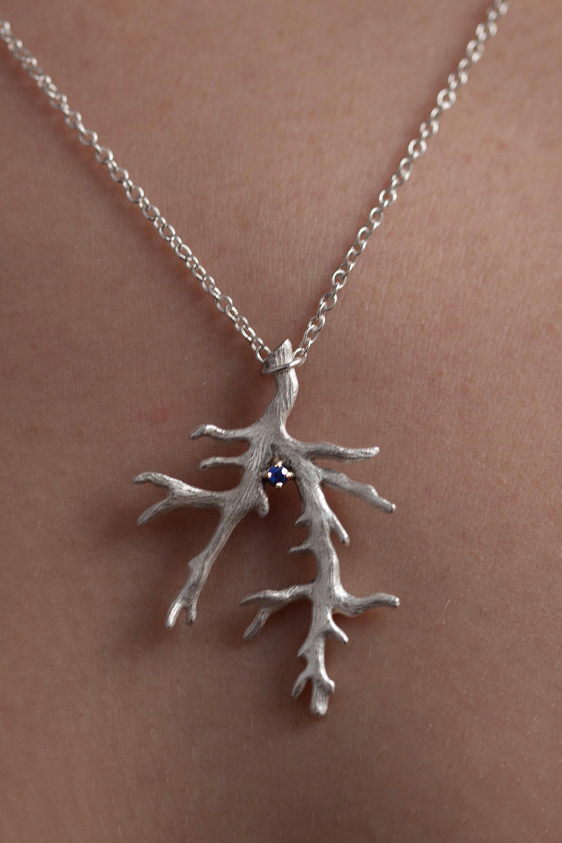 My branch pendant with a Sapphire, September's birthstone worn by a model, on a delicate trace chain can be worn at two lengths