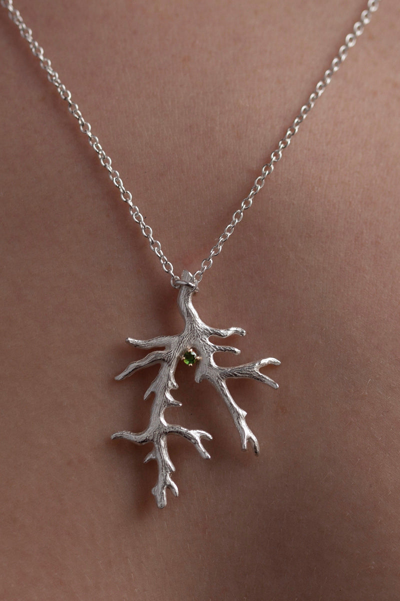 My branch pendant worn by a model, with a Green Tourmaline October's birthstone, on a delicate trace chain