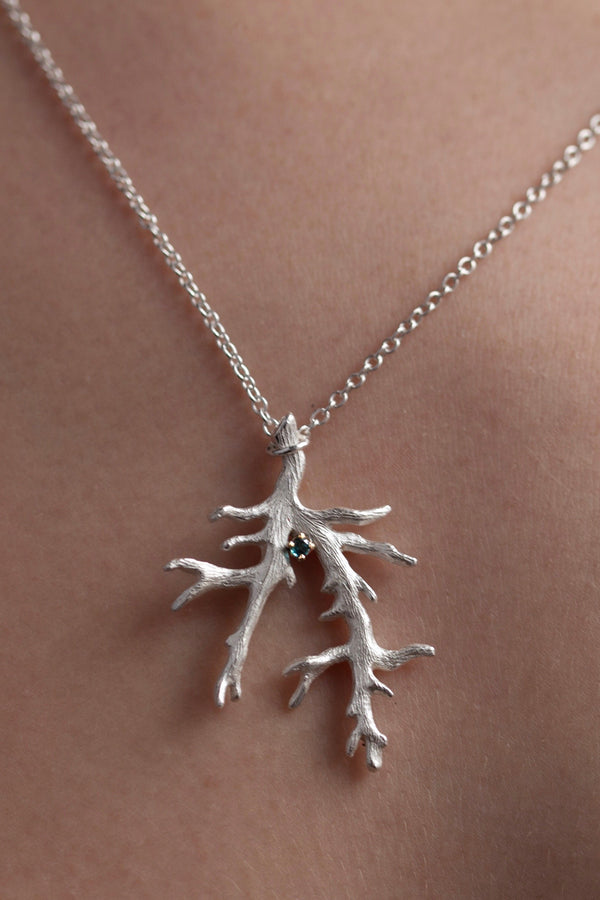 My branch pendant worn by a model, with a Blue Tourmaline October's birthstone, on a delicate trace chain