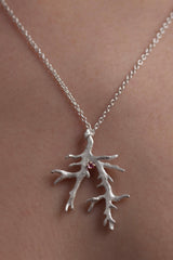 My branch pendant worn by a model, with a Blue Tourmaline October's birthstone, on a delicate trace chain