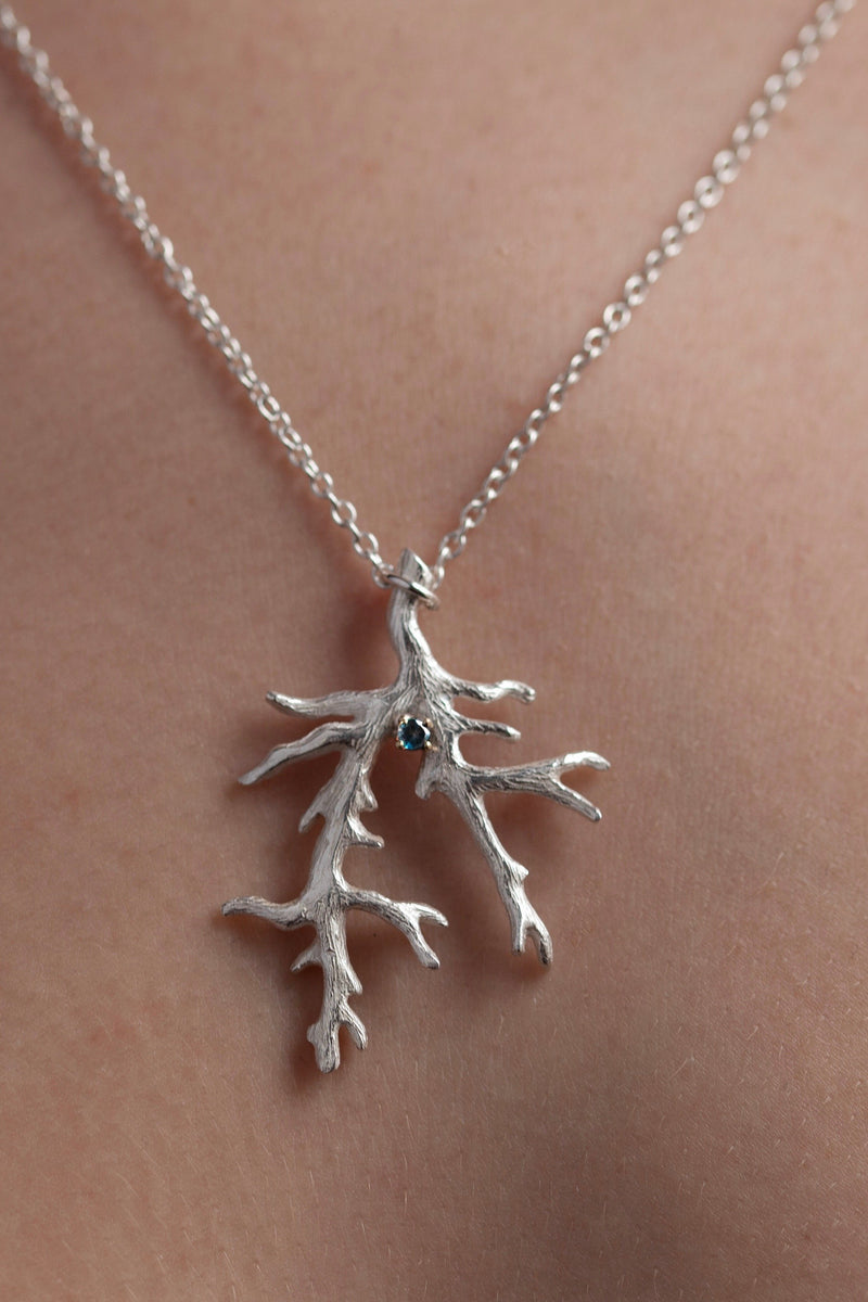 My unusual branch pendant worn by a model, with a London Blue Topaz November's birthstone, on a delicate trace chain