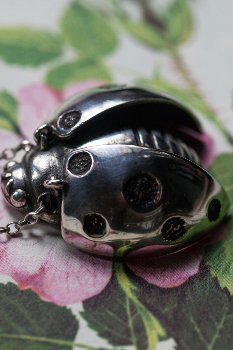 Close up of my Ladybird Pendant Necklace has a textured body and head with articulated wings and minute legs on the reverse