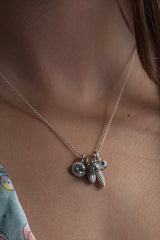 A dainty pendant worn by a model with a cluster of 5 silver pollen charms, 3 set with Swiss Blue Topaz, November's birthstone