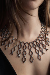 Kiss Cross collar style necklace worn by a model in oxidised silver made from interlocking cross shaped links