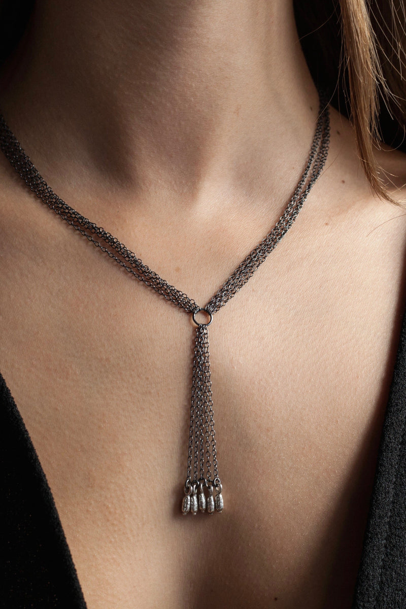 My Rice Pearl Necklace worn by a model features four oxidised silver chains with a central drop decorated with a group of bright silver rice pearl beads