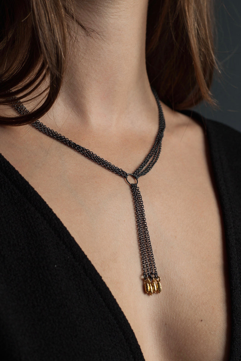 My Rice Pearl Necklace worn by a model features four oxidised silver chains with a central drop decorated with a group of contrasting gold plated rice pearl beads