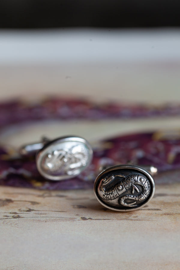 Chunky silver cufflinks with an intricate snake motif as their centrepiece.