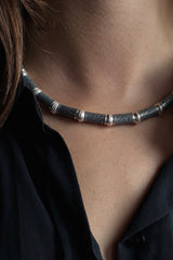 Worn necklace with textured beads alternating with striped round beads in contrasting silvers
