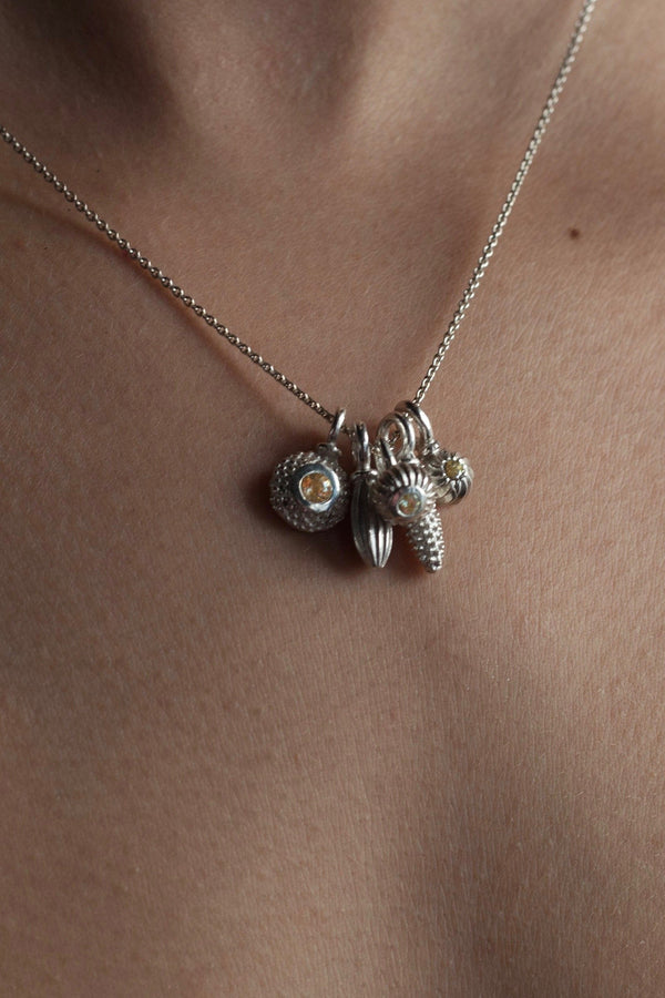 A dainty pendant worn by a model with 5 silver pollen charms, 3 set with a Yellow topaz November's birthstone