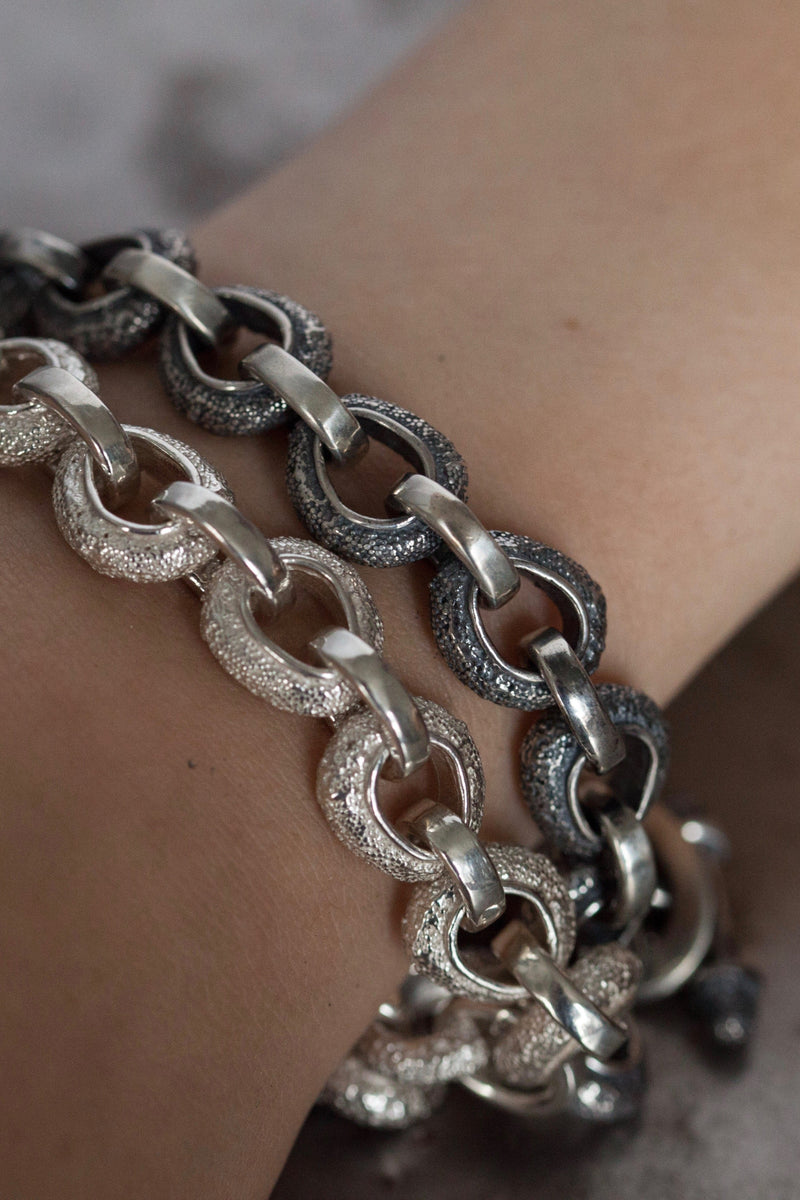 Pair of my bold Textured Oval Hoop Bracelet worn by a model in silver and oxidised silver