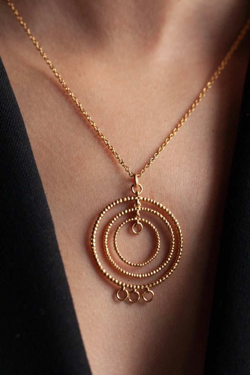 My Bubble Hoop Pendant, worn by a model in yellow gold plated silver, combines a trio of bobbled textured hoops decorated with three tiny hoops along the base to create an eye catching yet soft feminine design.