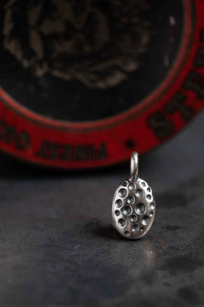 My ladybird charm is a small polished silver oval with different sized spots hanging from small silver ring