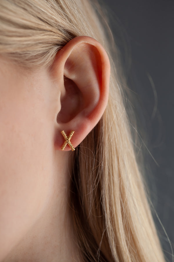 My Tiny Kiss Cross Studs worn by a model in gold plated silver
