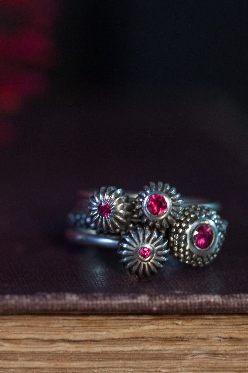 A set of 4 stacking rings featuring different pollen charms set with rubies July's birthstone 