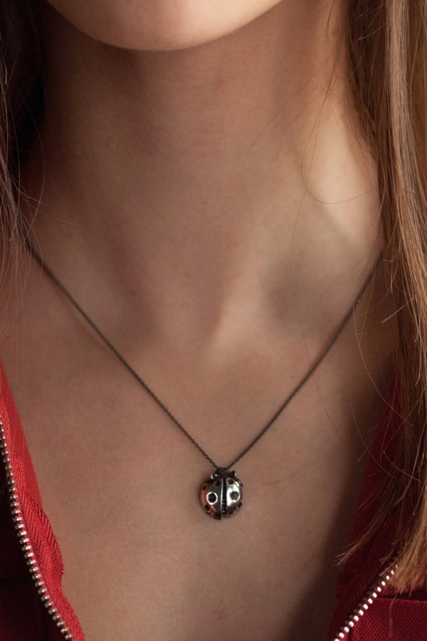 This little ladybird charm pendant worn by a model  has articulated wings and tiny legs on the reverse